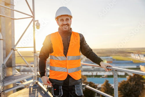 Portrait of an heavy industry worker standing on the height and smiling at the camera.