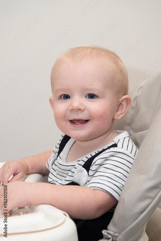 Baby smiles while eating his dinner in a highchair Baby smiles while eating his dinner in a highchair