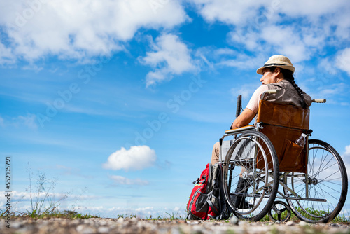 Asian male tourist. sitting in a wheelchair, looking at the beautiful scenery on the mountain, to people in wheelchair and backpacker concept.