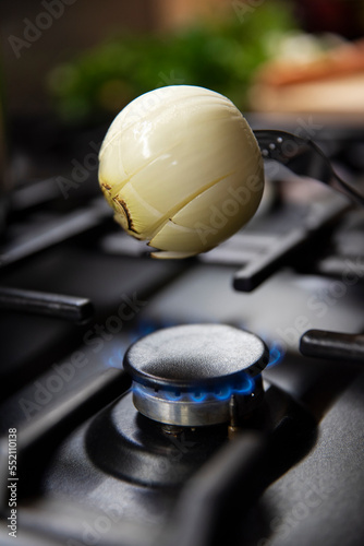 Opalanie cebulki do rosołu nad palnikiem na kuchence gazowej