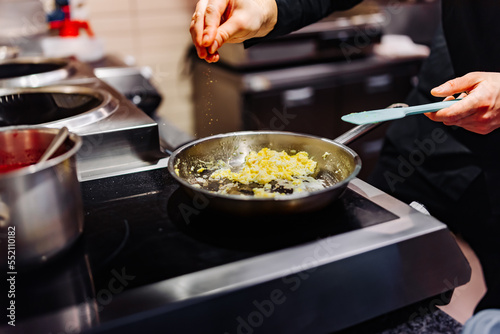 man chef cooking tasty scrambled eggs in frying pan on kitchen