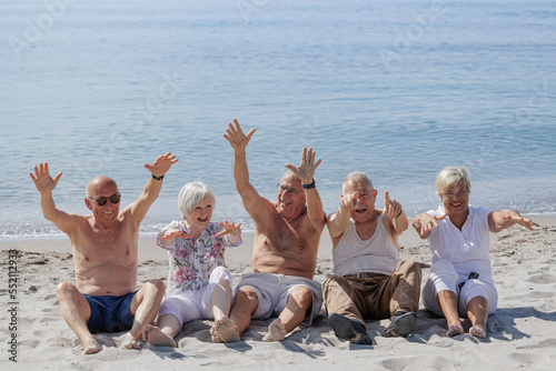 Un gruppo di anziani si diverte seduti nella spiaggia in riva al mare   photo