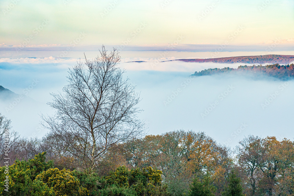 A view overlooking the mist filled valley of Horner Water to Bossington Hill and Minehead North Hill on Exmoor National Park at Cloutsham, Somerset, England UK