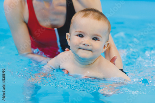 A swimming teacher teaches a little boy to swim in the pool. Children's first swimming lessons. Development for babies