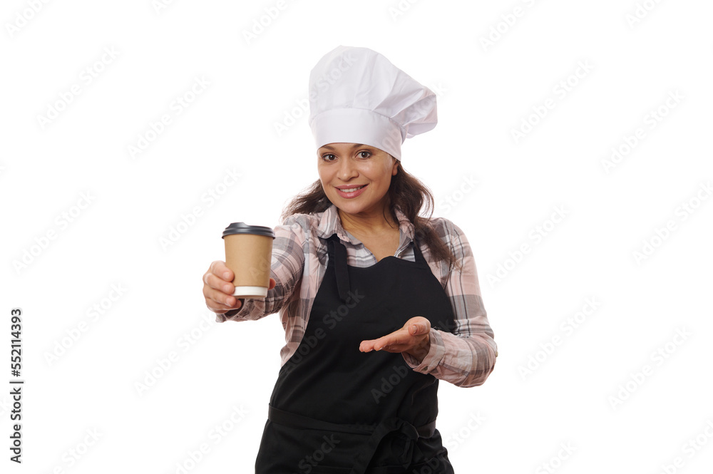 Pleasant female bartender waitress wearing chef hat and black apron, holding out hot drink to go, smiling on camera, isolated on white background. Food consumerism and delivery, coffee shops concept Pleasant female bartender waitress wearing chef hat and black apron, holding out hot drink to go, smiling on camera, isolated on white background. Food consumerism and delivery, coffee shops concept