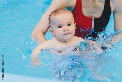A swimming teacher teaches a little boy to swim in the pool. Children s first swimming lessons. Development for babies