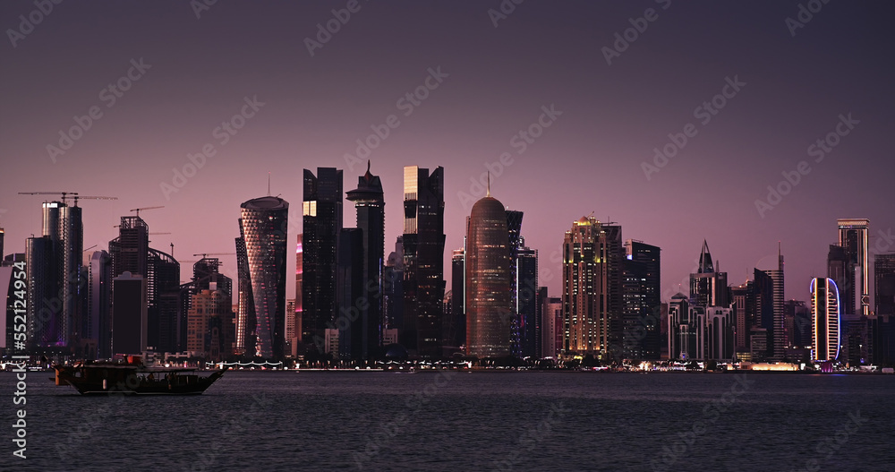 Obraz premium Traditional boat sail in Corniche area with amazing sunset view of cityscape skyscraper buildings in Doha, Qatar