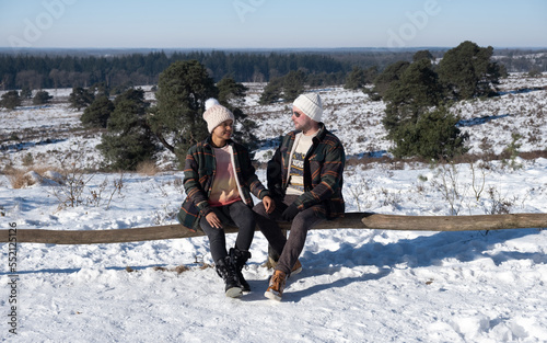 A Couple of men and women sitting in the snow during a cold winter day in the Netherlands at the Sallandse Heuvelrug national park photo