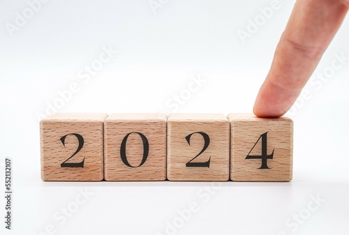 Hand choosing the number 2024 in wooden block cubes isolated on a white background. new year concept