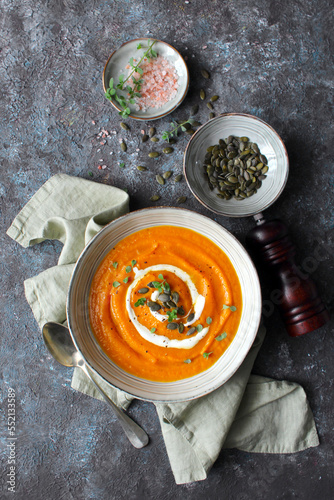 Pumpkin and carrot soup served with cream and seeds. Top view with copy space. Healthy food.