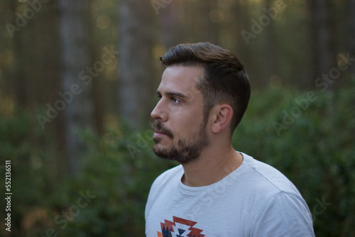Portrait of a handsome man in the middle of a forest at sunset