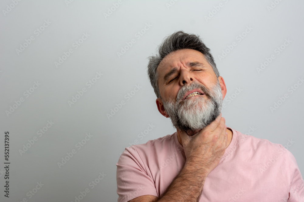 Fototapeta premium man having sore throat and touching his neck, wearing a t-shirt against light grey background. Hard to swallow