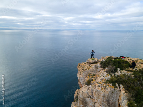 Person on cliff standing looking towards the horizon.