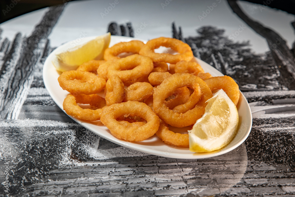 Roman squid with a piece of lemon served on a plate Roman squid with a piece of lemon served on a plate