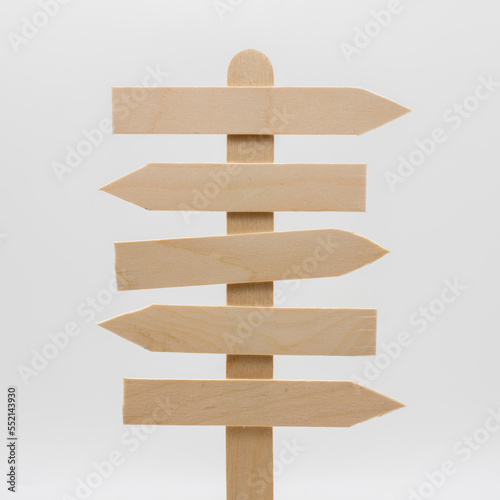 Poste indicador de cruce de caminos de madera con 5 flechas opuestas, sobre fondo blanco