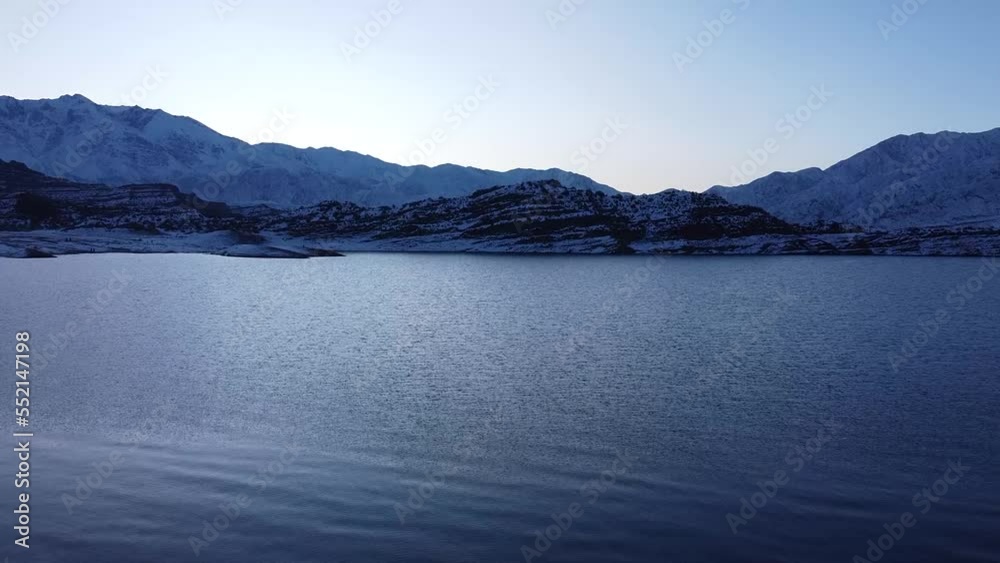 Aereal shot of a antarctic lake with snowed mountains. Sunset.