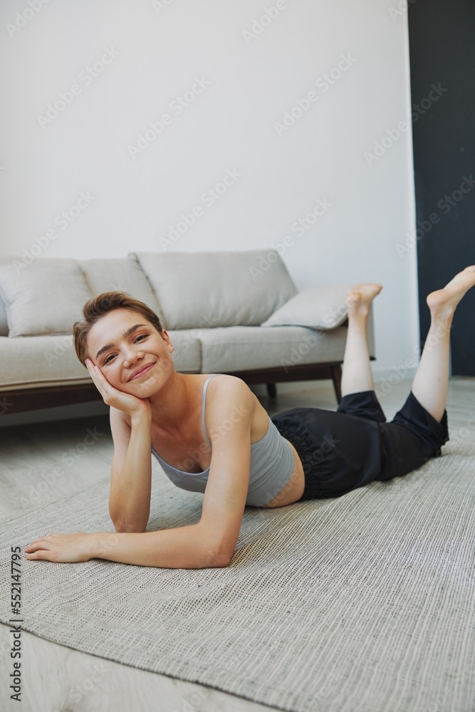 Teenage girl lying on the floor at home smiling in home clothes with a short haircut, lifestyle without filters, free copy space Teenage girl lying on the floor at home smiling in home clothes with a short haircut, lifestyle without filters, free copy space