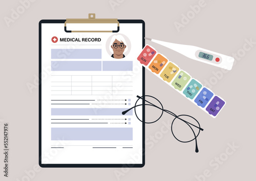 A set of senior patient's medical chart clipped to a clipboard, pill box, glass frames, and plastic thermometer