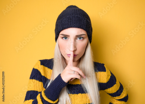 Psst. Young woman holding finger on lips, keep the secret concept, isolated on white background