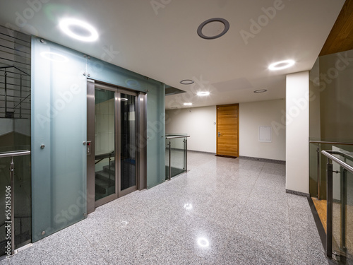Modern interior of entrance in luxury residential building. Wooden door. Elevator.
