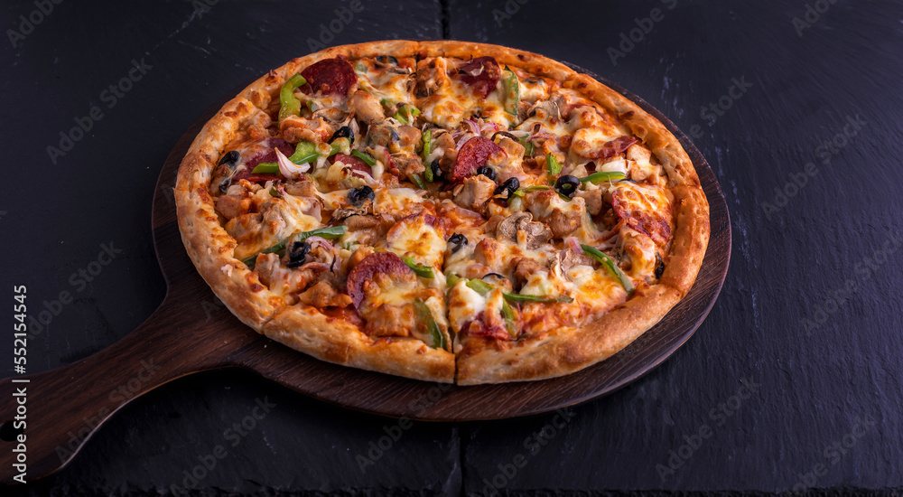 Chicken Supreme pizza isolated on cutting board top view on dark background italian fast food