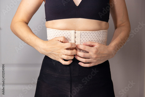 Diastasis recti after child birth. woman wearing a corset to support the abdomen during diastasis. Fitness exercises and diet for weight loss. Young woman side view of body.