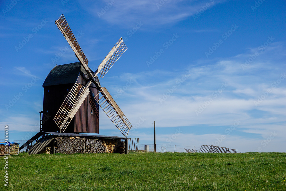 Fototapeta premium Windmühle an einer Wiese mit blauem Himmel