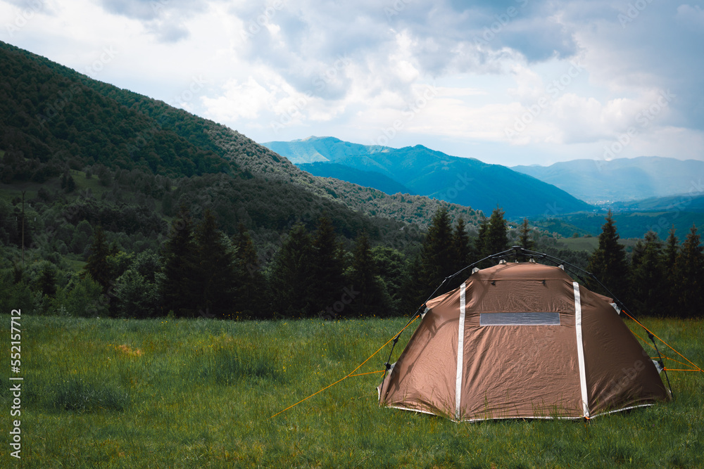 A brown tourist tent, with a quick-set system, stands on top of a mountain. A wonderful warm summer morning, the concept of freedom and travel.
