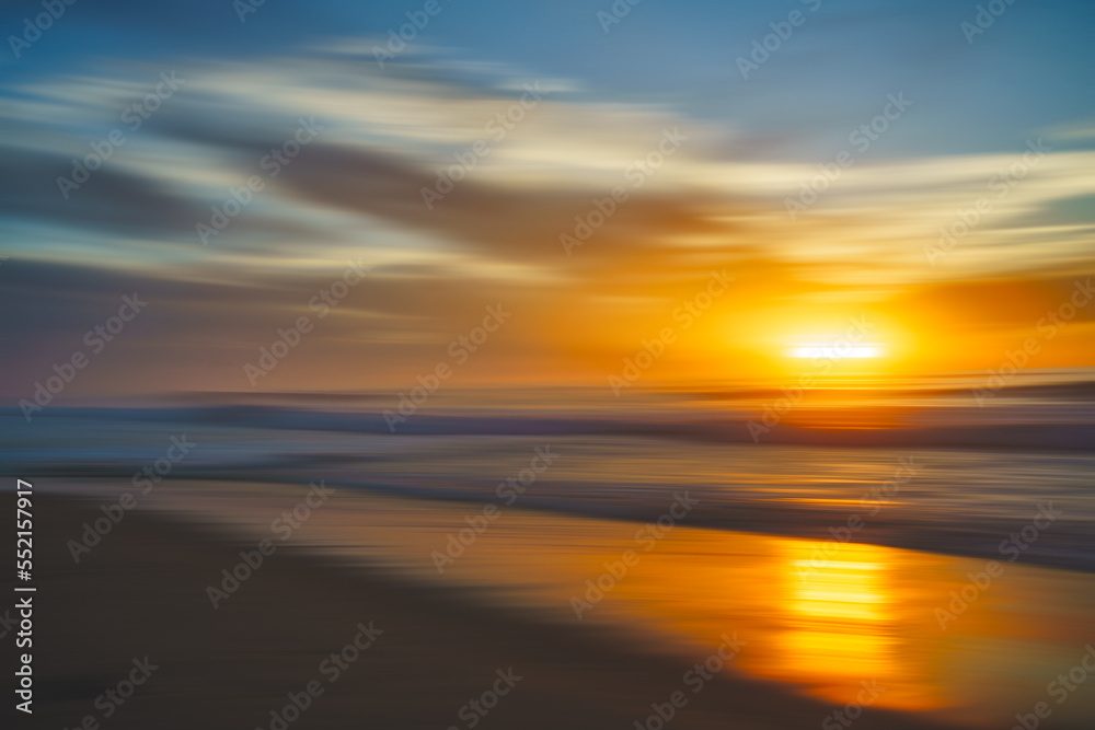 Abstract seascape. Tranquil scene of empty sand beach at sunset. Golden waves, sun reflections, motion blur, copy space