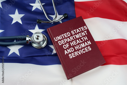 On the US flag lies a stethoscope and a book with the inscription -United States Department of Health and Human Services photo