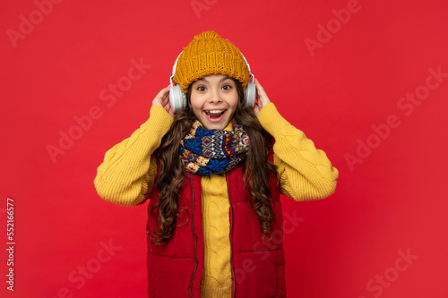 amazed child listen music in headphones. kid wear warm clothes. express positive emotion.