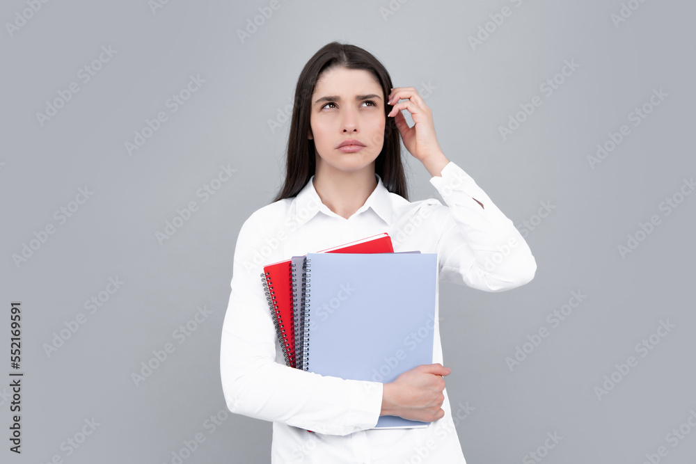 Angry young woman college student holding book on isolated gray background. Model emotionally showing facial expressions. Angry young woman college student holding book on isolated gray background. Model emotionally showing facial expressions.