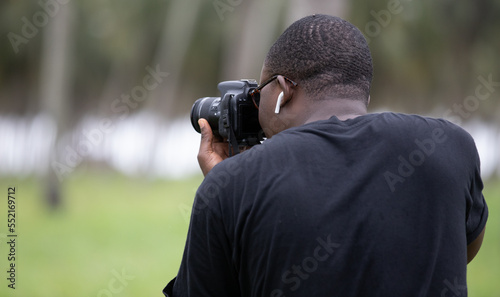 A young photographer takes pictures with a DSLR camera in an agricultural field in Africa. Professional self-employment