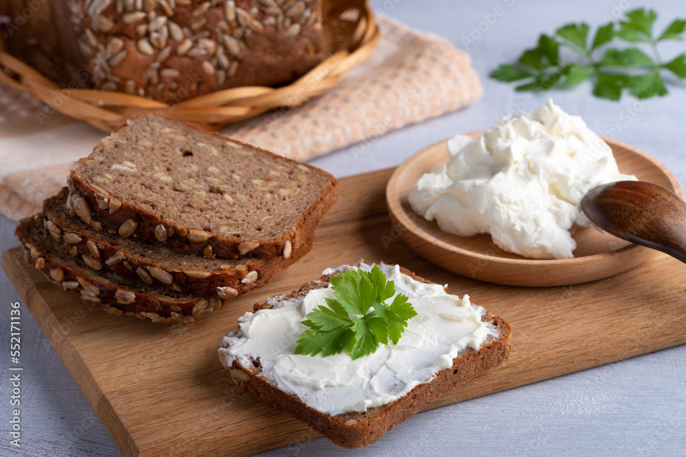 Home made rye bread on a wooden cutting board with curd cheese, ricotta and herbs. Home made rye bread on a wooden cutting board with curd cheese, ricotta and herbs.