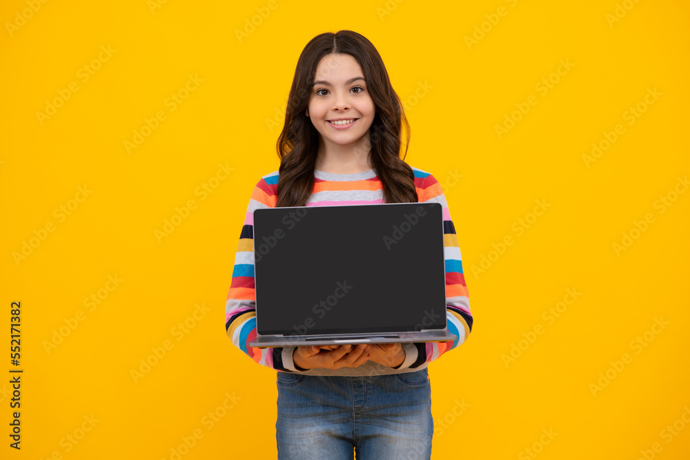 Excited face. Smart little boy with laptop in casual clothes isolated over yellow background. Screen of laptop computer with copy space mockup. Happy smiling teen school girl.