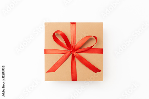 Flat lay of craft present box with red ribbon on the white background
