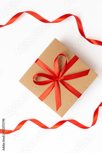 Flat lay of craft present box with red bow and ribbons on the white background