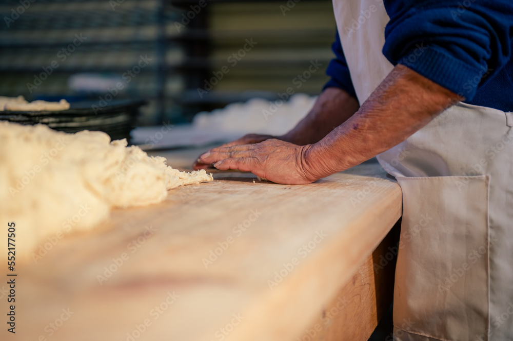 Manos de un hombre trabajando con masa y harina de trigo en una panaderia. Manos de repostero.