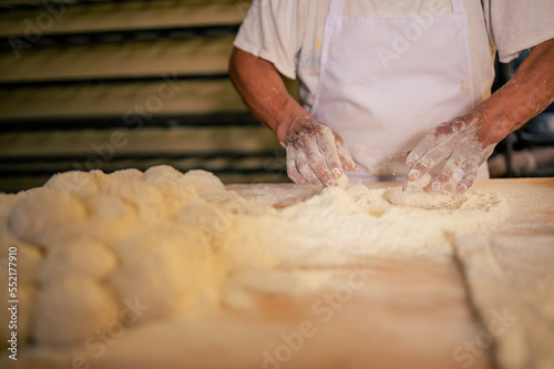 Hombre trabajando con masa y harina de trigo en una panaderia artesanal. Hombre Latino en una panaderia.