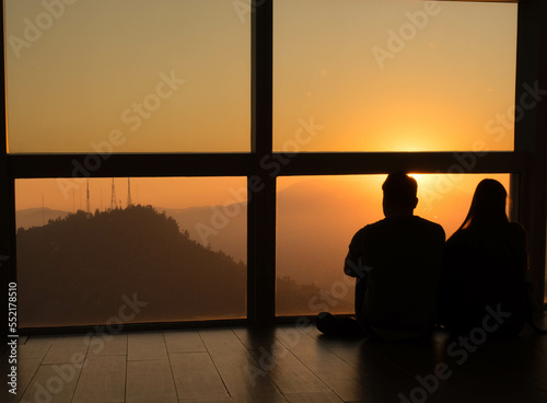 couple watching the sunset sitting in a viewpoint of a skyscraper © benjamin