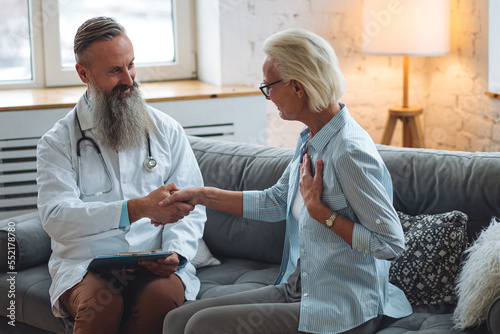 Male doctor visiting attractive senior woman at home for consultation, medical service and support, geriatric help, prescribing illness treatment