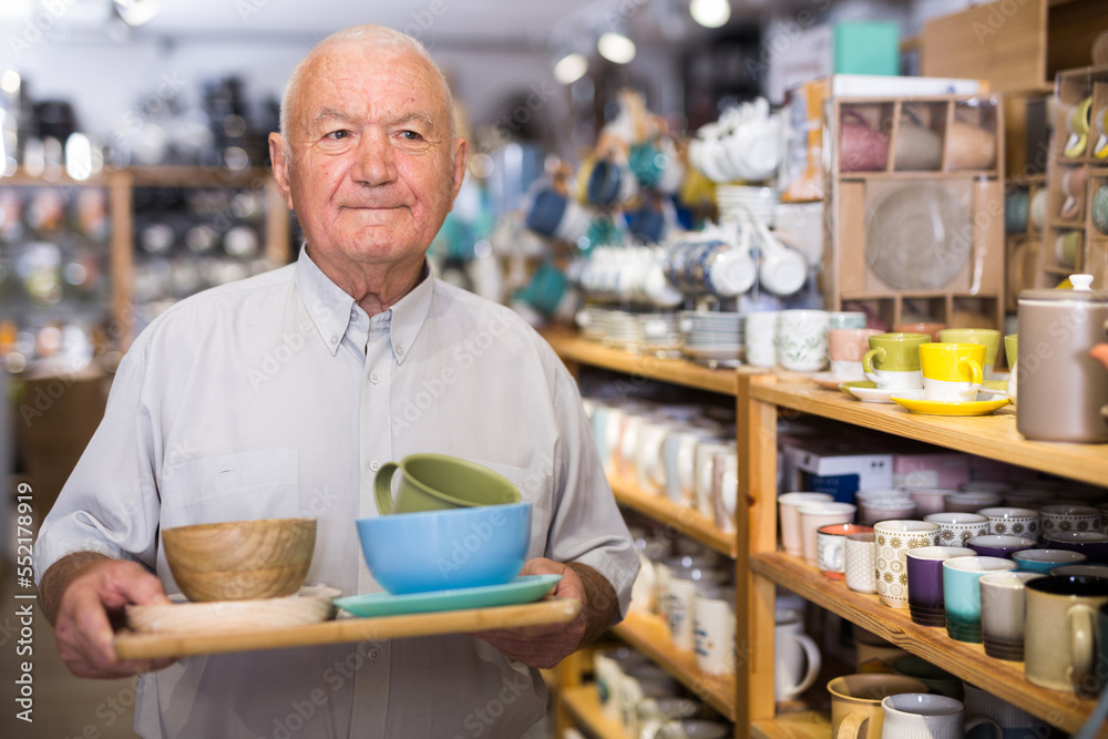 Portrait of senior man with purchases in hands in tableware store