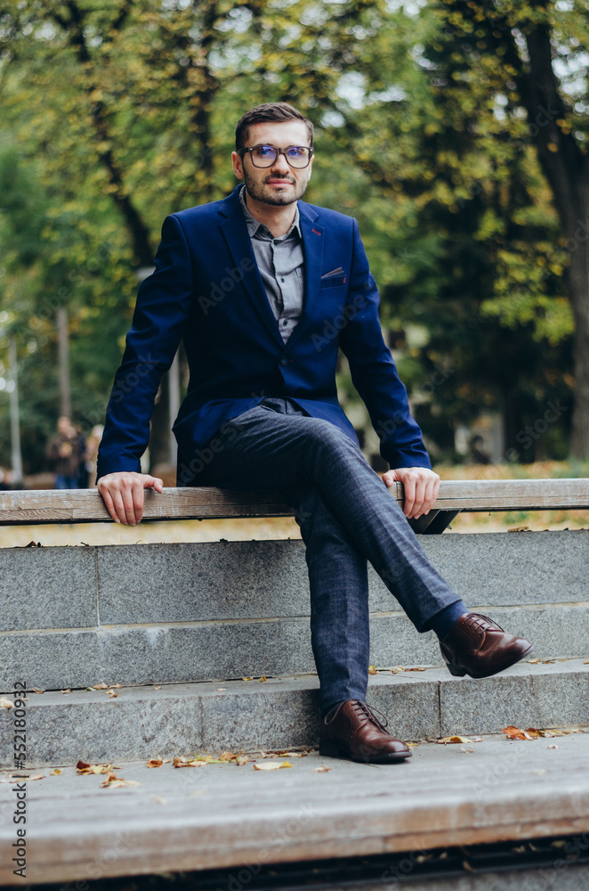 A man in a suit is sitting on a bench in the park A man in a suit is sitting on a bench in the park