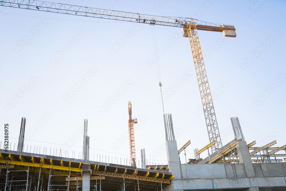 Construction site with monolithic concrete yellow and gray frame scaffolding and yellow construction tower cranes on the background. Construction concept.