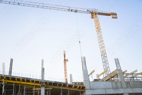 Obraz na płótnie Construction site with monolithic concrete yellow and gray frame scaffolding and yellow construction tower cranes on the background. Construction concept. w salonie