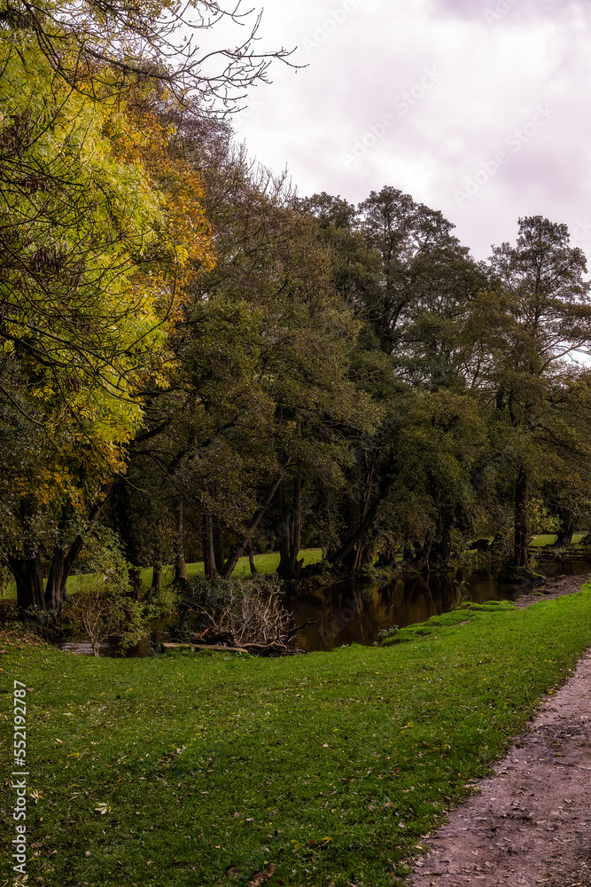 Walking along the river Derwent in autumn, trees reflecting in the Goit, Derbyshire, England
