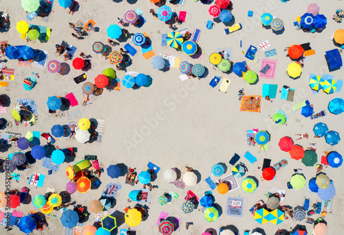Aerial view of colorful umbrellas on sandy beach, people at sunset in summer in Sardinia, Italy. Tropical landscape. Travel and vacation. Top down view from drone. Concept. Background for text
