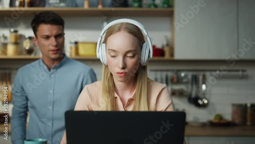 Business woman working home on laptop with headset man trying distract closeup