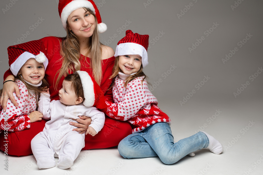 Obraz premium Family, mom and kids at Christmas. A beautiful woman, a mother with many children with children in the studio in red Christmas outfits and Santa hats