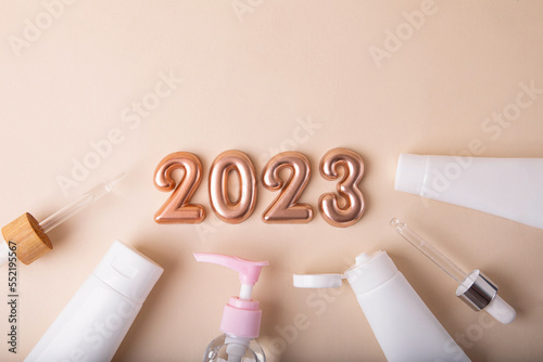 Top view of the cosmetics containers on pastel background.Rose gold numbers 2023 above.Good for new year offer and text overlay. photo
